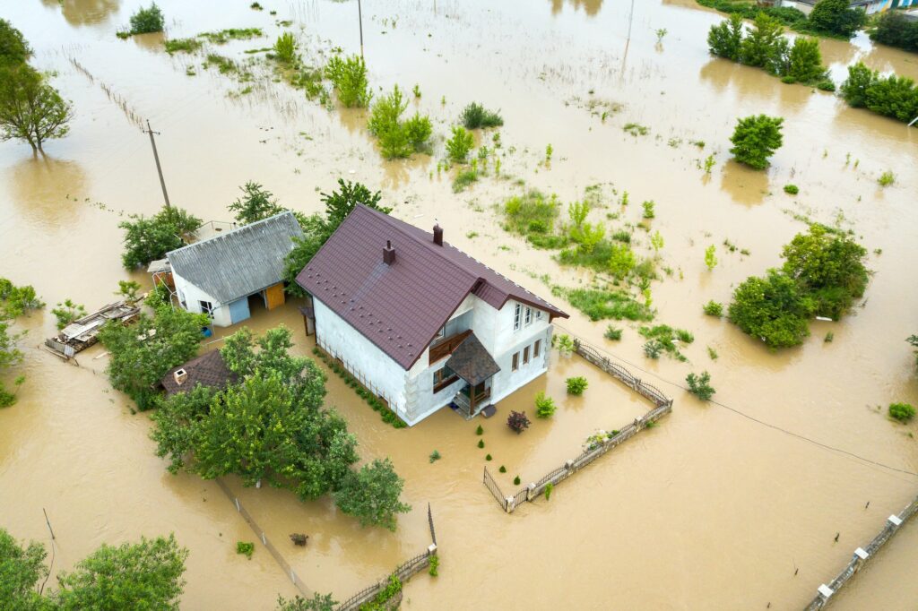 Aerial view of flooded house with dirty water all around it.