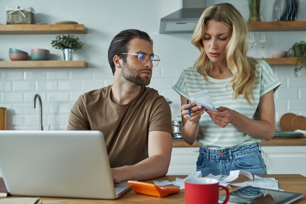 Beautiful young couple going over financial bills while sitting at the domestic kitchen